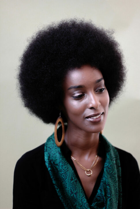 Ladan Osman in a black top with a green scarf, large earrings and a necklace