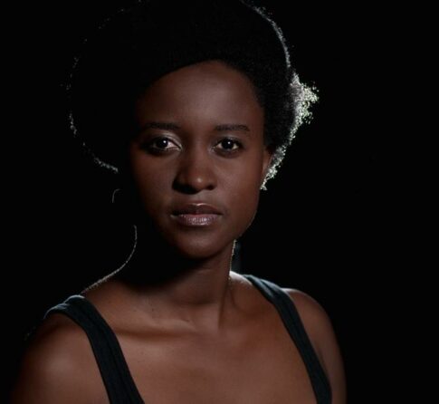 Poet Tjwangwa (TJ) Dema faces the camera with a serious expression, standing in front of a black background